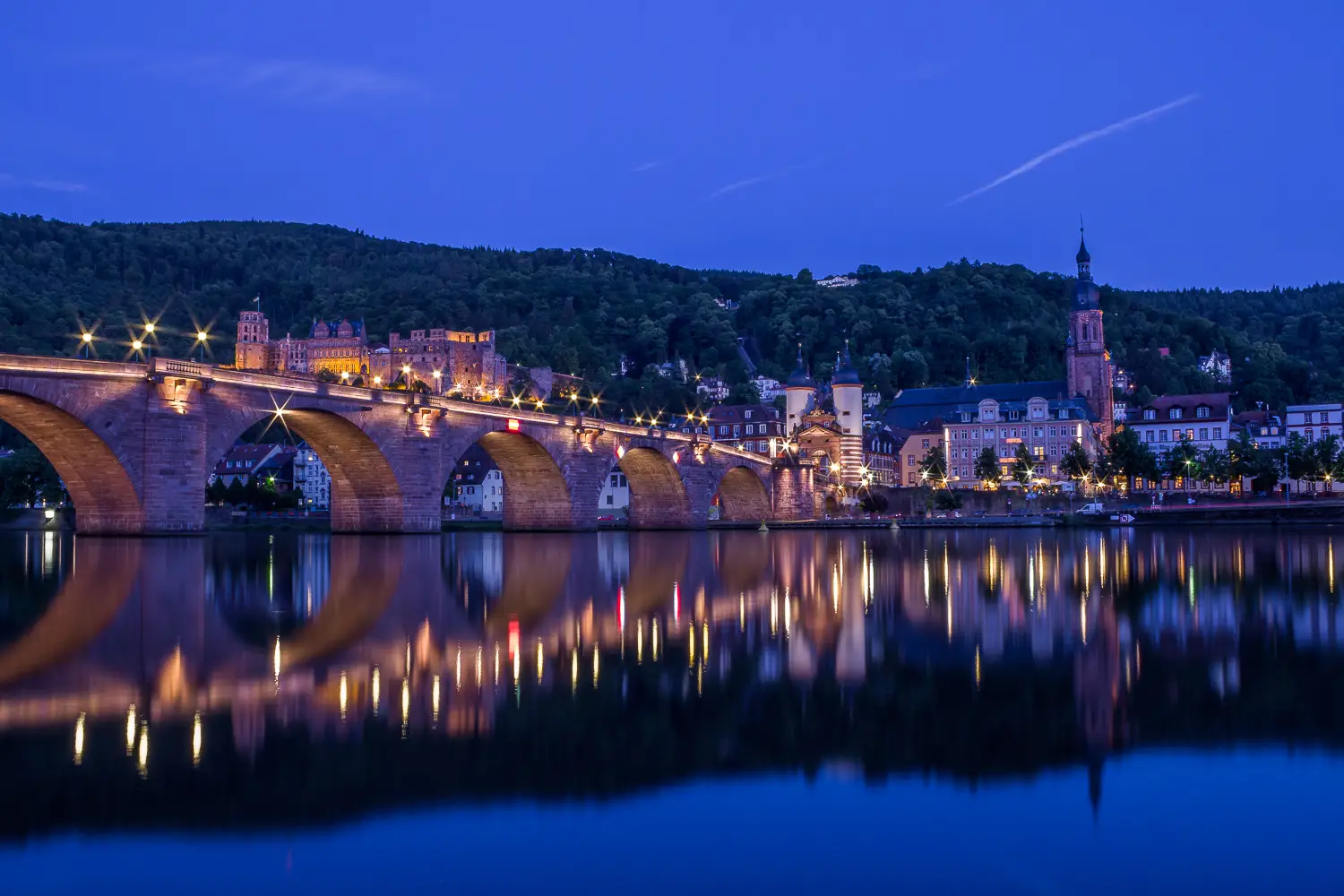 Alte Brücke und Heidelberger Altstadt zur blauen Stunde, Lichter spiegeln sich im Neckar