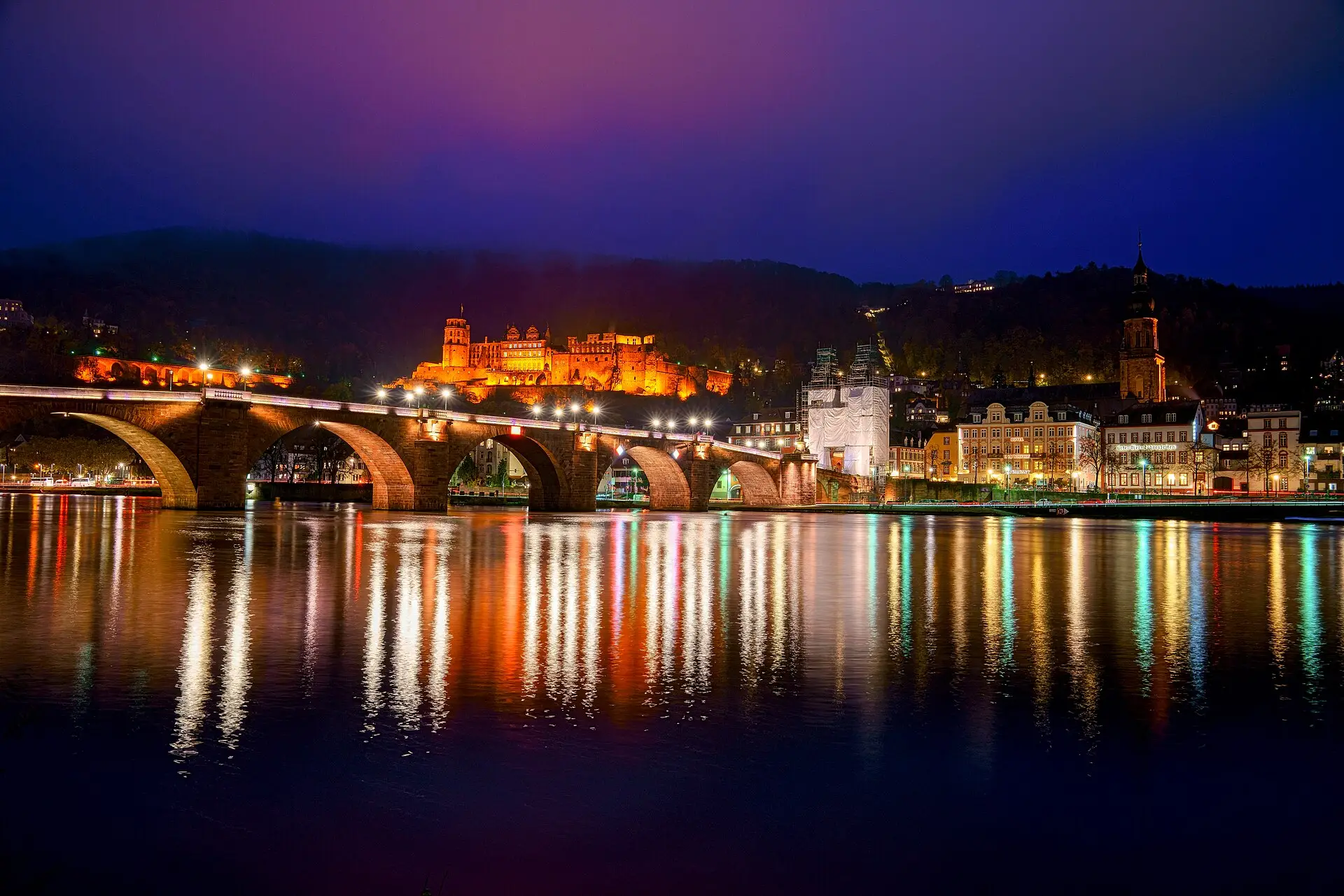 Alte Brücke, Brückentor und Altstadt mit bunten Lichtreflexen im Neckar bei Nacht