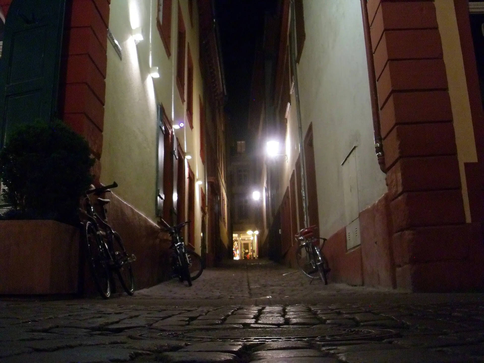 Schmale Altstadtgasse mit Kopfsteinpflaster und Laternenlicht bei Nacht